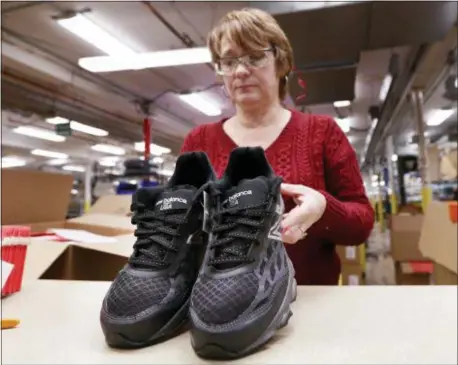  ?? ROBERT F. BUKATY — THE ASSOCIATED PRESS ?? In this Monday photo, Ruby Williams inspects a pair of athletic shoes designed for the military at a New Balance factory in Norridgewo­ck, Maine. The new contract fulfills a federal law requiring the military to outfit new recruits with American-made apparel.