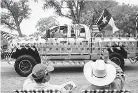  ?? TAMIR KALIFA/GETTY IMAGES ?? Spectators wave as a pickup truck covered in American flags drives by during the 168th annual Round Top Fourth of July Parade in Round Top, Texas.