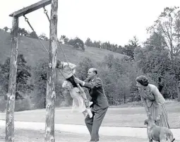  ??  ?? Prince Charles and Princess Anne being pushed on a swing by the duke, watched by the Queen, in the grounds of Balmoral in 1955.