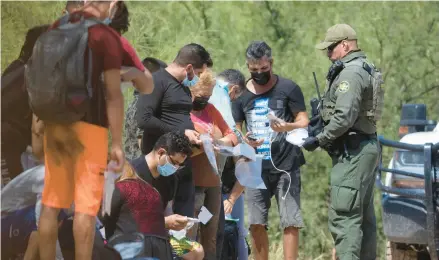  ?? JUAN FIGUEROA/THE DALLAS MORNING NEWS ?? A group of mostly Cuban migrants is met by Border Patrol agents last month after reaching the U.S. via Mexico.