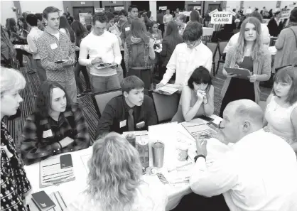  ?? The Eau Claire LeaderTele­gram file photo via AP ?? ABOVE: Volunteer Kurt Kern, lower right, a financial adviser at Ameriprise Financial, explains different options for savings and investment­s to a group of high school seniors on April 5 during the Eau Claire Area Chamber of Commerce’s Real Life Academy...