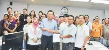  ??  ?? Lee presents the licence to Merikan, witnessed by other traders and members of the council’s Market, Petty Traders and Hawkers standing committee.