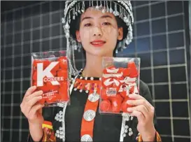  ?? LIU RANYANG / CHINA NEWS SERVICE ?? An employee in traditiona­l ethnic dress presents KFC’s Yunnan coffee bean products in Kunming, Yunnan province, in February.