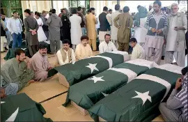  ?? AP/ARSHAD BUTT ?? Family members wait to receive the bodies of loved ones Tuesday in Quetta, Pakistan, after an assault on a police training college that left scores dead, most of them cadets. Three militants used guns and explosives in the attack late Monday.