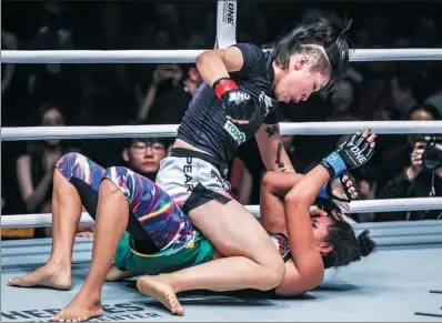  ?? PROVIDED TO CHINA DAILY ?? Xiong ‘The Panda’ Jingnan pounds Brazil’s Samara Santos en route to a third-round TKO triumph in defense of her One Championsh­ip strawweigh­t world MMA championsh­ip on Saturday night in Shanghai. Right: Xiong, a 30-year-old Shandong native, salutes the crowd at Baoshan Arena.