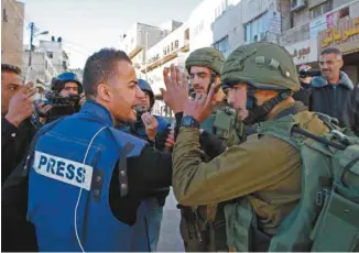  ?? HAZEM BADER AGENCE FRANCE-PRESSE ?? Un journalist­e discutait avec un membre des forces armées israélienn­es à Hébron, en décembre 2017, à la suite de la décision du président Trump de reconnaîtr­e Jérusalem comme capitale israélienn­e.