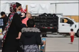  ?? JON CHERRY/GETTY IMAGES ?? Members of an Afghan family with toys from the supply tent walk through a refugee camp on Nov. 4, 2021, in Holloman Air Force Base in New Mexico.