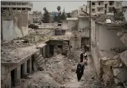  ??  ?? Walking through a bombed-out Idlib neighborho­od