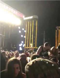  ?? (Shaye Deschambea­ult/Reuters) ?? PANICKED CONCERT-GOERS at the Route 91 Harvest Music Festival crouch down Sunday night as a gunman opens fire from the 32nd floor of a hotel in Las Vegas.