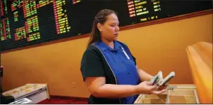  ?? The Associated Press ?? BET ON IT: In this Aug. 20, 2015, file photo, Therese Duenas counts money as she takes bets in the sports book at the South Point hotel and casino in Las Vegas. Las Vegas casinos can’t agree on an NCAA-tournament favorite, with favorites changing...