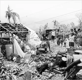  ?? MARCO UGARTE THE ASSOCIATED PRESS ?? A family stands near their damaged home and debris in the aftermath of hurricane Willa, in Escuinapa, Mexico. Emergency workers on Oct. 24 were struggling to reach beach towns left incommunic­ado by a blow from Willa.