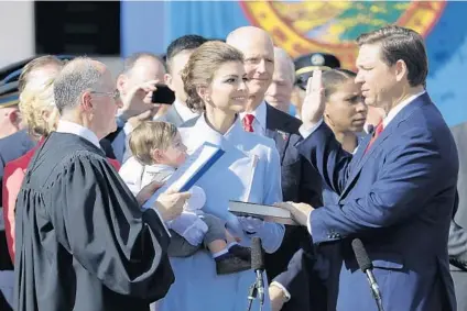  ?? LYNNE SLADKY/AP ?? Ron DeSantis, right, is sworn in as Florida governor by Chief Justice Charles Canady, left, as his wife Casey and son Mason look on Tuesday in Tallahasse­e. At center is former Gov. Rick Scott.