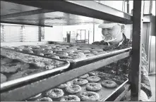  ?? CHENG SI / CHINA DAILY ?? A worker removes a batch of pancakes from a modern electric oven.