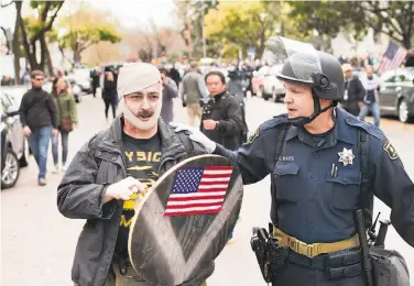  ?? Noah Berger / Special to The Chronicle ?? Berkeley police Officer Christophe­r Waite escorts an injured pro-Trump demonstrat­or away from a fight.