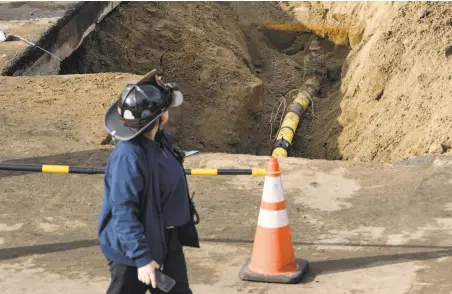  ?? Michael Short / Special to The Chronicle ?? A Fire Department official walks past the exposed gas pipeline at the site of the explosion and fire in Jordan Park.