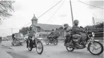  ?? REUTERS ?? Motorcycle taxis ride past the area where a mass grave was identified, following an investigat­ion by the Truth and Reconcilia­tion Commission, in Kamenge neighbourh­ood, Bujumbura, Burundi on Thursday.