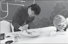  ??  ?? Right: Li Wenyue, a Jingdezhen porcelain maker from Jiangxi province, creates a painting on a plate at the expo.