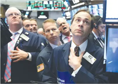  ?? AP PHOTO/RICHARD DREW ?? Dudley Devine, right, works with fellow traders last week on the floor of the New York Stock Exchange. On Tuesday stocks closed sharply lower on Wall Street as a rout in major technology companies continued.