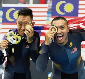  ??  ?? Sweet win: Mohd Amin Najmi Romzi and Mohd Firdaus Mohd Zonis celebratin­g their victory after winning the 4000m individual pursuit (B) event at the National Velodrome in Nilai,