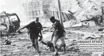  ??  ?? Two men carry the body of a victim following the explosion of a truck bomb in the center of Mogadishu, on Saturday afternoon.