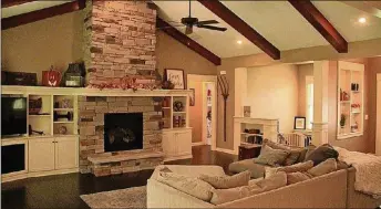  ??  ?? The foyer leads into the great room, which has a cathedral ceiling, wood beam accents that match the wood flooring, recessed lighting and ceiling speakers. A stone fireplace has a raised stone hearth and wood mantel that blends into the adjoining entertainm­ent center and cabinetry.