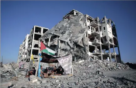  ?? Picture: AP ?? Palestinia­n Ziad Rizk sits with others in a shelter made of a blanket stretched over four poles next to one of the destroyed al-Nada Towers, where he lost his flat and clothes shop, in the town of Beit Lahiya, northern Gaza Strip.