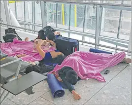  ?? Steve Parsons The Associated Press ?? Travelers rest on the floor in Terminal 5 at Heathrow Airport on Friday. The airport had to cancel or delay flights because of severe weather and a technical issue.