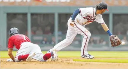  ?? AP PHOTO/TAMI CHAPPELL ?? The Washington Nationals’ Trea Turner dives back to second base as Atlanta Braves shorstop Braves Dansby Swanson chases down the ball in the fourth inning Sunday in Atlanta.