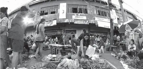  ?? FREEMAN FILE PHOTO ?? Vendors and consumers trade outside the dilapidate­d Tabunok market building in Talisay City. The constructi­on of a new one was among the banner proposals of Mayor Johnny De los Reyes but the project has been stalled owing to funding issues.