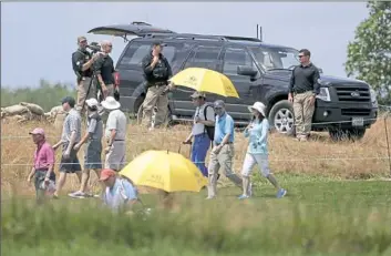  ?? Seth Wenig/Associated Press ?? Golf spectators walk past presidenti­al security during the third round of the U.S. Women's Open Golf tournament on Saturday in Bedminster, N.J.