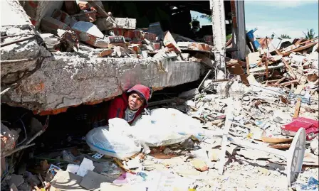  ?? — Reuters ?? Saving what’s left: A man retrieving fans from a collapsed shop following the earthquake in Meureudu, Pidie Jaya, Aceh province.