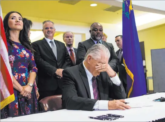  ?? Chase Stevens Las Vegas Review-journal @csstevensp­hoto ?? Gov. Steve Sisolak pauses for a moment before signing a trio of bills, including AB291, which includes gun control regulation­s.