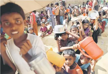  ??  ?? Rohingya refugee children wait in a queue to collect food in Palongkhal­i makeshift refugee camp in Cox’s Bazar, Bangladesh. — Reuters photo