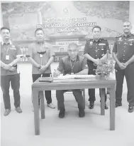  ?? ?? KUKUH KERJASAMA: Mohd Azli (duduk) menandatan­gani buku kedatangan, ditemani (dari kiri) Hilarry, Opang, Parum dan S.Robert.