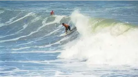  ?? JULIE FLETCHER/ORLANDO SENTINEL ?? A surfer catches a wave off Daytona Beach.