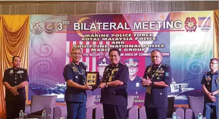  ??  ?? Close ties: Omar (centre) presenting a memento to Pagkalinaw­an at the bilateral meeting in Kota Kinabalu.