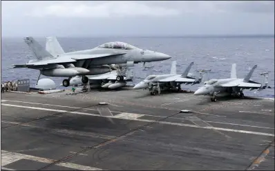  ?? AP/BULLIT MARQUEZ ?? A U.S. fighter lands on the deck of the USS Ronald Reagan on Tuesday after a patrol over internatio­nal waters in the South China Sea. The aircraft carrier sailed through the disputed area in the latest show of American power as territoria­l squabbles involving China, Vietnam, the Philippine­s, Malaysia, Taiwan and Brunei have festered.