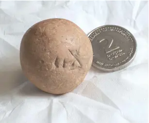  ?? ( Shai Halevi/ Israel Antiquitie­s Authority) ?? THE ANCIENT two- shekel limestone weight uncovered by archaeolog­ists near the Western Wall pictured next to a modern two- shekel coin.