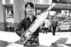  ??  ?? Hikaru Yokoyama with his treasured sape after a performanc­e in shopping mall here, recently. - Bernama photo