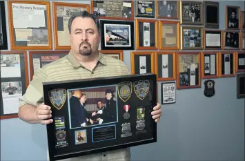  ?? HANS GUTKNECHT — STAFF PHOTOGRAPH­ER ?? Marc Manfro holds a framed collage of shields, photos and medals from his service in the New York Police Department. Manfro retired from the NYPD after 17years and moved to Castaic with his family. He was on duty during Sept. 11, 2001.