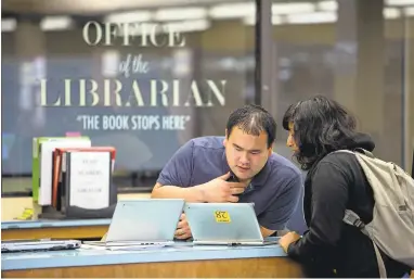  ?? LIPO CHING/STAFF PHOTOS ?? Overfelt High School math teacher and Saturday staff coordinato­r Lawrence Yee, left, helps Jennifer Hernandez, 17, navigate a Chromebook at the school library in San Jose. The school district is working to bring internet access to more students’ homes.