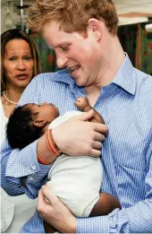  ??  ?? Babe in arms: Harry cradles a sick child at a children’s hospital in Barbados