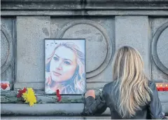  ?? AP ?? A woman places flowers next to a portrait of slain television reporter Viktoria Marinova during a vigil at the Liberty Monument in Ruse, Bulgaria.