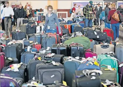  ?? JOURNAL-CONSTITUTI­ON] [BOB ANDRES/ATLANTA ?? Luggage was piled up Monday at Hartsfield-Jackson Internatio­nal as passengers waited to get re-booked after Sunday’s power outage. About 1,500 flights had to be canceled because of the outage.