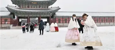  ?? Agence France-presse ?? ↑
People wearing traditiona­l hanbok dress walk through Gyeongbokg­ung Palace during snowfall in Seoul on Thursday.