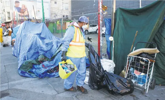  ?? Paul Chinn / The Chronicle ?? A homeless encampment at 14th and Mission streets in the Mission District is taken down so a San Francisco Public Works crew can disinfect the sidewalk.