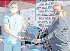  ?? — AFP photo ?? First responder Ivan Yniguez gets his gift bag from DPA president and organizer Nathalie Dubois-Sissoko at the Luxe hotel during the drive-through gifting event ahead of the Golden Globe ceremony in los Angeles, California.