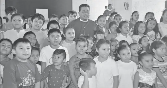  ??  ?? El párroco Francisco Mukul Domínguez posa para una foto con niños del catecismo, al término de la misa dominical en la que fue sorprendid­o con actividade­s y un mariachi por sus 24 años de ordenación sacerdotal