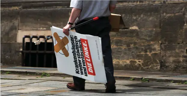  ?? Foto: dpa/Arno Burgi ?? Ein Mann trägt am im Mai 2014 in Dresden ein Wahlplakat der Linksparte­i weg. 7,4 Prozent der Stimmen hatte DIE LINKE bei der letzten Europawahl geholt.
