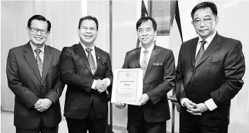  ??  ?? Ik Pahon (second left) hands over some notes to Hii in a symbolic handing-over of duties while Abdul Karim (right) and Lee look on. — Photo by Chimon Upon